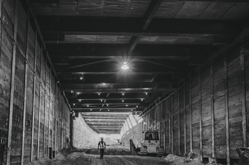 A worker walks down a long subterranean corridor